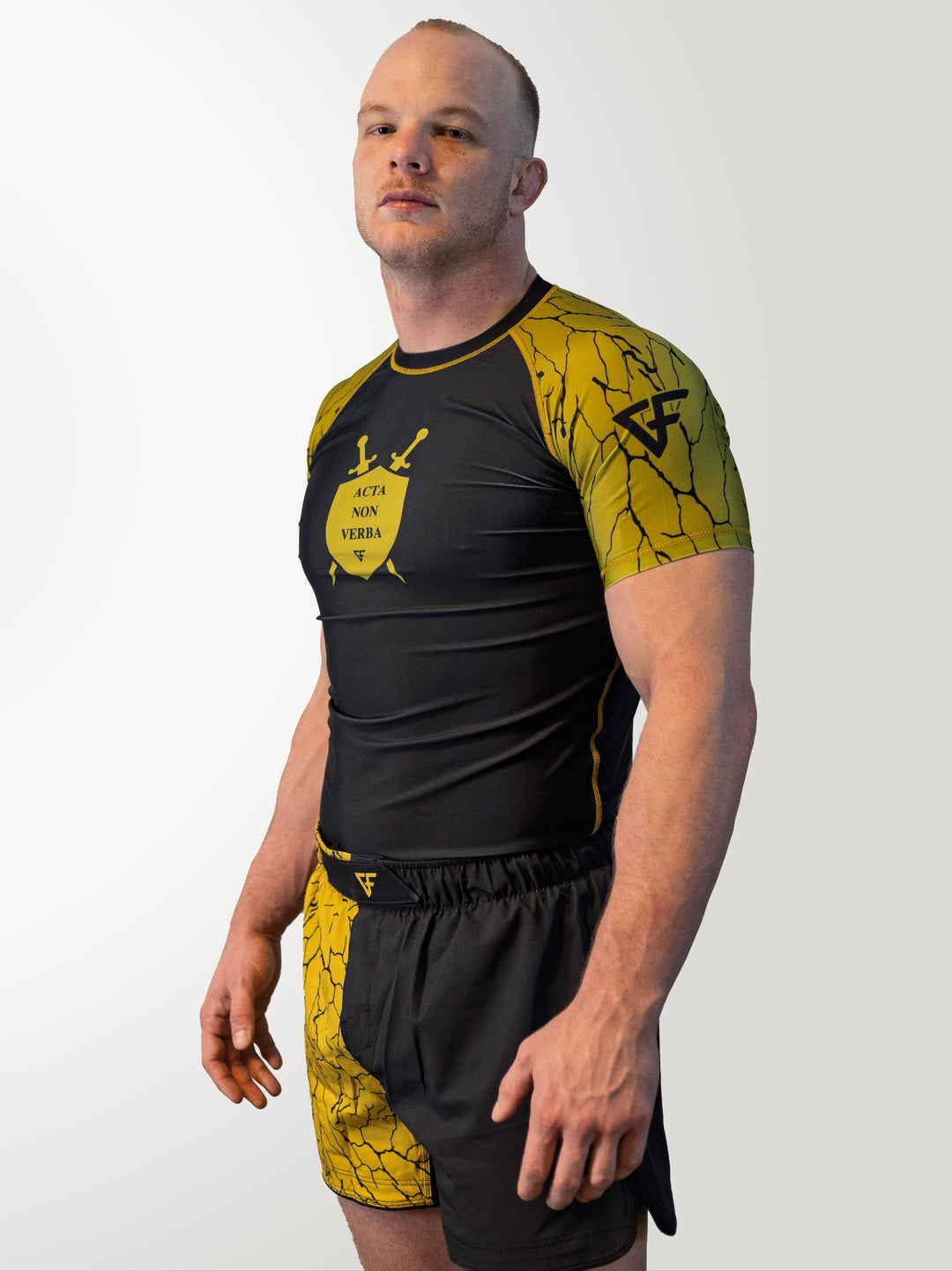 Man wearing a black and yellow athletic outfit with a logo on a white background