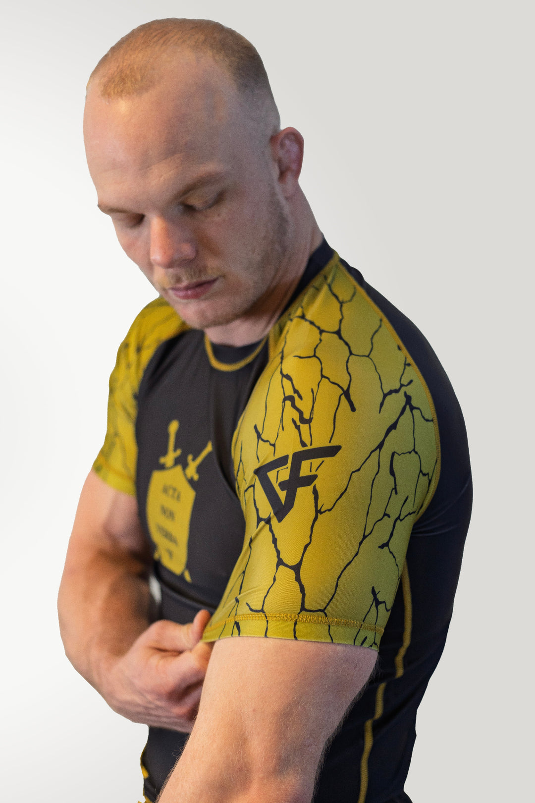 Man wearing a black and yellow athletic shirt with a logo on a white background